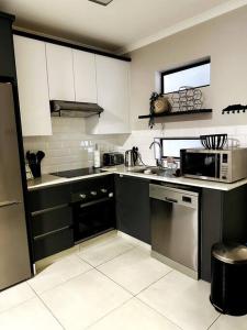 a kitchen with black and white cabinets and appliances at Aries self-catering Unit in Centurion