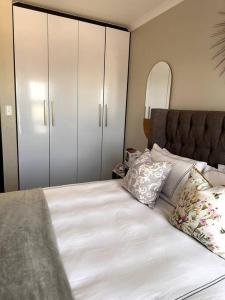 a bedroom with a bed with white sheets and pillows at Aries self-catering Unit in Centurion
