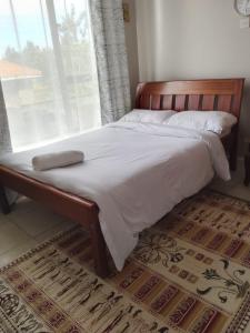 un lit dans une chambre avec une grande fenêtre dans l'établissement CultureStays, à Kiambu