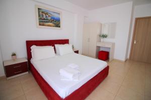 a bedroom with a white bed with a red headboard at Afrimi Relax Apartments in Sarandë