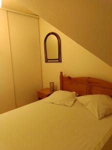 sypialnia z łóżkiem z drewnianym zagłówkiem i lustrem w obiekcie Appartement au coeur de Luchon w mieście Luchon