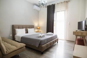 a bedroom with a bed and a couch and a television at HILI RESORT LUXURIOUS SEASIDE APARTMENT in Alexandroupoli