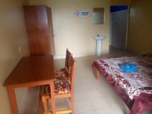 een kamer met een bed, een tafel en een wastafel bij Prudent Guest House in Isuvya
