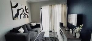 een woonkamer met een bank en een televisie bij Serenity in Pretoria
