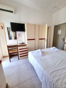 een slaapkamer met een groot wit bed en een televisie bij Due Gemelle in Rimini