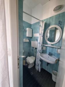 W łazience znajduje się umywalka, toaleta i lustro. w obiekcie Due Gemelle w Rimini