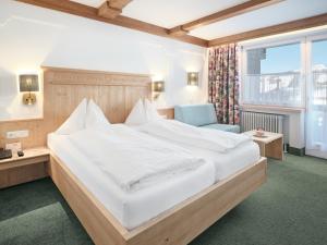 a bedroom with a large white bed and a blue chair at Genuss - und Vitalhotel Moisl in Abtenau