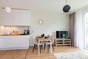 a kitchen with white cabinets and a table and chairs at Golden Sand - Baltic Line in Gdańsk