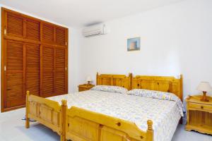 1 dormitorio con cama de madera y puertas de madera en Can Granada, en Es Pujols