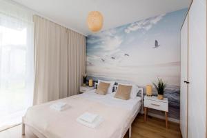 a bedroom with a bed with a painting of the ocean at Golden Sand - Baltic Line in Gdańsk +13 photos