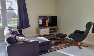 uma sala de estar com um sofá e uma cadeira e uma televisão em Sunshine Studio em Hamilton