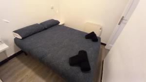 Dormitorio pequeño con cama con sábanas y almohadas negras en Apartamento Forn Vell en Sant Feliu de Guixols