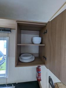 a small kitchen with plates in a tiny house at 3 Bedroom Caravan, Sleeps 8 Lyons Lido Beach in Prestatyn