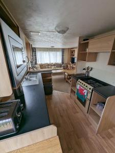 Il dispose d'une cuisine et d'un salon avec des plaques de cuisson. dans l'établissement 3 Bedroom Caravan, Sleeps 8 Lyons Lido Beach, à Prestatyn