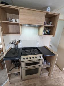 a kitchen with a stove and a counter top at 3 Bedroom Caravan, Sleeps 8 Lyons Lido Beach in Prestatyn