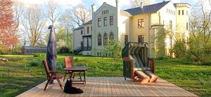 Un chat noir assis sur une terrasse en face d'une maison dans l'établissement Herrenhaus Harmshagen, à Testorf-Steinfort