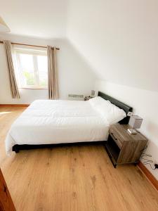 Schlafzimmer mit einem großen weißen Bett und Holzboden in der Unterkunft Brittas Bay Village No 7 in Brittas Bay