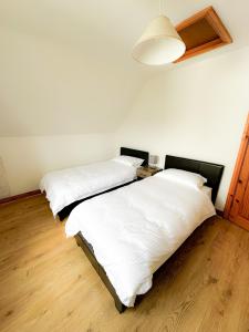 Zimmer mit 2 Betten, weißer Bettwäsche und einer Lampe in der Unterkunft Brittas Bay Village No 7 in Brittas Bay