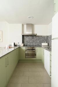 uma cozinha com armários verdes e piso em azulejo em Racons - La Placeta em Vic