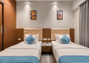 two beds in a hotel room with blue pillows at J Square Inn in Coimbatore