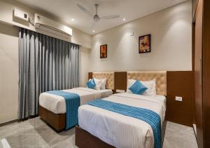 a hotel room with two beds and a window at J Square Inn in Coimbatore