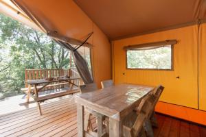 a dining room with a table and a bench on a deck at Lodge du Berlandou in Escragnolles