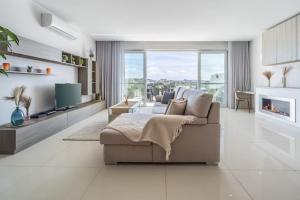 sala de estar blanca con sofá y TV en Modern 3 Bedrooms Penthouse With A Breathtaking Valletta View, en Sliema
