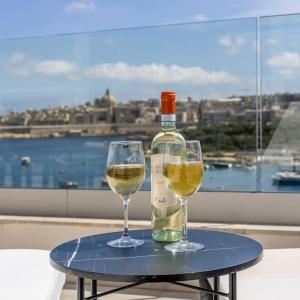 Una botella de vino y dos copas en una mesa. en Modern 3 Bedrooms Penthouse With A Breathtaking Valletta View, en Sliema