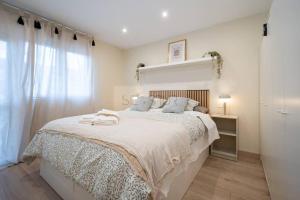 um quarto branco com uma cama grande e uma janela em Montes Suites em Gijón