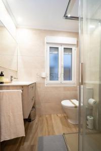 uma casa de banho com um WC, um lavatório e uma janela em Montes Suites em Gijón