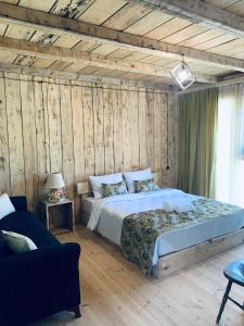 1 dormitorio con 1 cama en una habitación con paredes de madera en Korenishuli Veranda Wine Hotel, en Tsʼageri