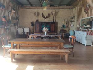 une salle à manger avec des tables, des chaises et des bois sur le mur dans l'établissement La Valise A Cheval, à Mézières-sur-Ponthouin