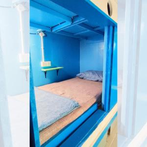 Bestow Capsule Hostel في كوالالمبور: غرفة بسرير في غرفة زرقاء