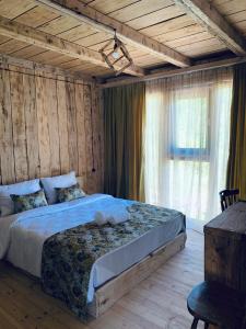 een slaapkamer met een bed en een groot raam bij Korenishuli Veranda Wine Hotel in Tsʼageri