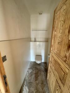 a bathroom with a toilet and a wooden door at Appartement à 2 pas de la plage in Olmeto +16 photos