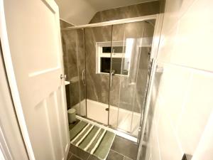 een douche met een glazen deur in de badkamer bij 4 Bedroom House near City Centre with Parking in Gloucester