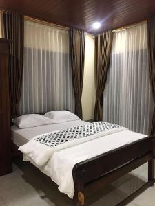 ein Schlafzimmer mit einem großen Bett mit Vorhängen in der Unterkunft Mbah Oden Homestay Borobudur in Mendut