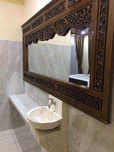 ein Bad mit einem Waschbecken und einem Spiegel in der Unterkunft Mbah Oden Homestay Borobudur in Mendut