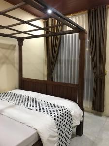 a bedroom with a bed with a wooden canopy at Mbah Oden Homestay Borobudur in Mendut
