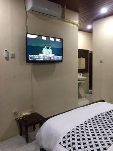 a bedroom with a tv on a wall with a bed at Mbah Oden Homestay Borobudur in Mendut