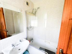ein weißes Bad mit einem Waschbecken und einer Dusche in der Unterkunft Brittas Bay Village No 7 in Brittas Bay