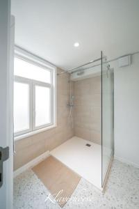 een badkamer met een douche en een glazen deur bij Klaverhoeve Stene in Oostende