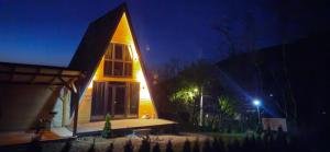 une maison avec une fenêtre éclairée la nuit dans l'établissement E&T-Cabin A frame, à Sibiu