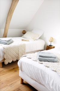 two beds in a room with white walls at La Ferme 1802 in Sainghin-en-Mélantois