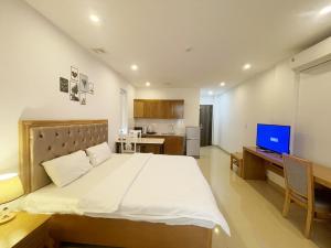 een slaapkamer met een groot bed en een bureau met een computer bij GEM Apartment & Hotel in An Khê