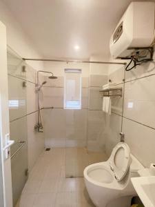 uma casa de banho branca com um WC e um chuveiro em GEM Apartment & Hotel em An Khê