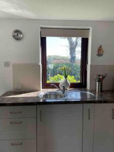 a kitchen counter with a sink and a window at Cosy cottage between Penzance and St Ives in Gulval