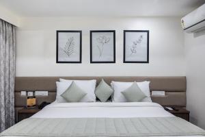 a bedroom with a bed with four pictures on the wall at Aashreya Suites Tiruvannamalai in Tiruvannāmalai