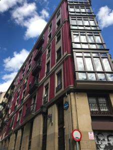 un edificio alto de color rojo con ventanas en una calle en Monappart Cristo Historic Apartment with Parking, en Bilbao