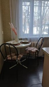 een tafel en 2 stoelen in een keuken met een raam bij 2 комнатная квартира в центре города in Karagandy
